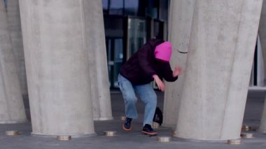 Kentsel bir ortamda, iki insan beton sütunlar arasında dostça iletişim kurarak, canlı bir atmosferi vurguluyor.