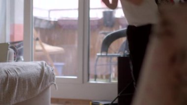 Video, rahat bir oturma odasında, pencereden dışarı bakan genç bir çocuk ve sürgülü kapıdan dışarı bakan bir yetişkinin ev hayatını aktardığı huzurlu bir anı tasvir ediyor.