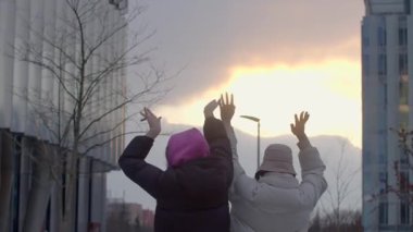 Bir grup insan çarpıcı bir şehir manzarasına karşı gün batımını seyrediyor ve eğleniyor.