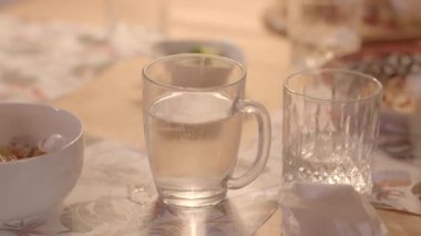 Bu video, yemek ve bir bardak suyu olan bir masadaki bir kişinin yakın çekimleri ile huzurlu bir yemek deneyimi sergiliyor.