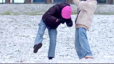 İki birey güzel, karlı bir arka planda birlikte yürürken neşeyle el ele tutuşuyorlar.