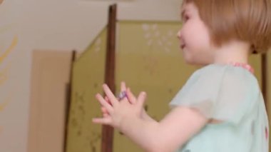 Kahkaha dolu sıcacık bir ortamda, genç bir çocuk mutlu bir şekilde elini sallıyor. Gözden ırak birine. O güzel anda neşeli bir nişan ve saf neşe sergiliyor.