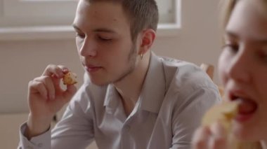Bu video, sıcak bir masada yemek ve sohbetten zevk alan bir çifti gösteriyor. Patates kızartması ve pizza gibi, kahkaha ve şefkat dolu.