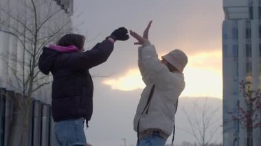 Büyüleyici gün batımında şehir ortamında neşeli etkileşim içinde olan iki birey