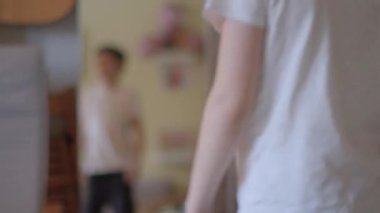 Balonlu canlı bir odada tesettürlü bir kadın bir erkekle ayakta duruyor. Bir erkek ve bir kız bir anı paylaşırken, diğeri aynada yansıyor.