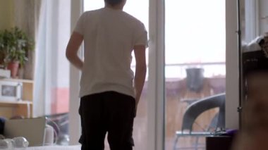 Pencerenin yumuşak doğal ışıklarıyla dolu kapalı bir ortamda neşeyle dans eden genç bir insan.