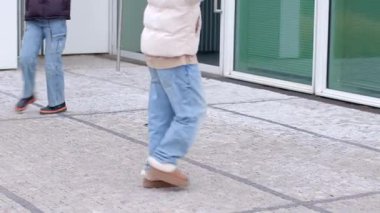 İki neşeli çocuk, cam arka planlı, güzel ve modern bir binanın dışında oyun oynuyorlar.