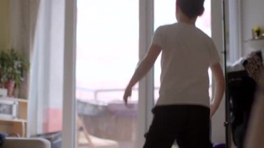 Bir çocuk rahatça balkon kapısına yaklaşırken sıcak ve kapalı bir çevreyi keşfediyor.