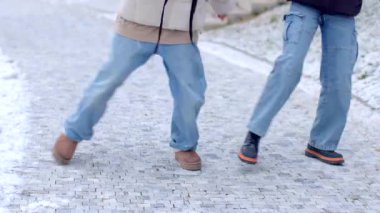 İki insan kış kıyafetleriyle karlı bir yolda yürüyor, soğuk ve sakin manzaranın tadını çıkarıyorlar.