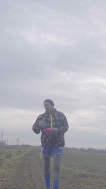 Genç bir adam açık bir alanda elinde güzel bulutlu bir arka planı olan bir cihaz tutarken duruyor.