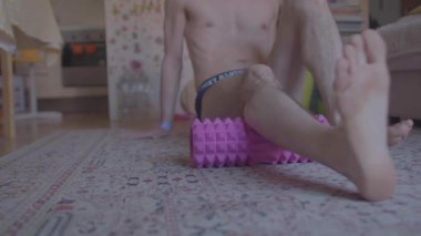 Bir adam oturma odasındaki halıyı süngermek için köpük rulo kullanır, esnekliği ve kas yenilenmesini arttırır.