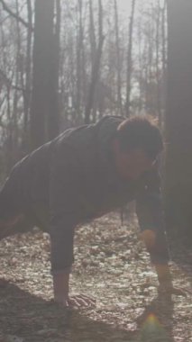 Bir adam, doğada zindelik ve refahı teşvik eden bir orman zeminine karşı şınav çekiyor.