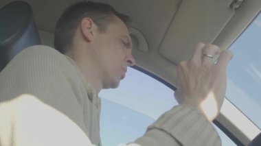 Bir adam araba kullanırken akıllı telefonunu kullanır ve dikkati dağılmış araba kullanmanın modern sorununu gösterir.