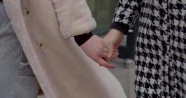 Kentsel bir ortamda, iki birey el ele tutuşuyor, bağlarını ve sevgilerini gösteriyorlar.