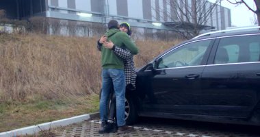 Şehir merkezinde park halindeki bir otomobilin yanında iki kişi sohbet ediyor.