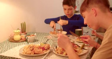 İki mutlu çocuk, sıcak bir atmosferde lezzetli yiyeceklerle dolu güzel bir masada yemeğin tadını çıkarıyorlar.