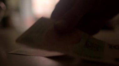 Yumuşak ve bulanık bir arka plan sahneyi hazırlarken bir el nazikçe düz bir yüzeye birden fazla banknot yerleştiriyor.