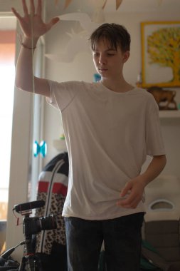 Genç bir insan, arka plan ve ayarlarla dolu bir odada cam bir yüzeyle etkileşime girer.