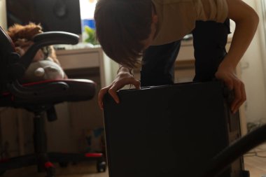 Bir sandalyede rahatça oturan bir kişi var, ve arka planda, etrafta gezinen bir kedi görülebilir.