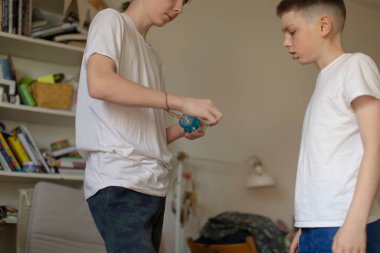 İki genç çocuk içeride bir objeyle oynuyorlar, arka planda raflar görünüyor.