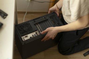 Bir birey, dinamik bir çalışma alanındaki bağlantı noktaları ve kablolarına odaklanarak bir bilgisayar kutusu oluşturur.