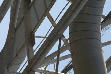 Bu, üzerinde uzanan açık mavi gökyüzü ile güzelce zıt düşen metalik bir yapının detaylı bir yakın görüntüsü.