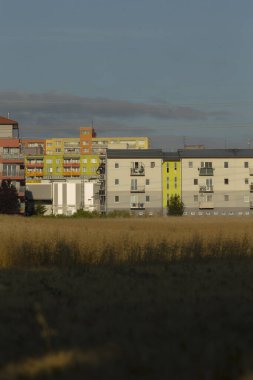 Ön planda, geniş bir alan var. Arkasında uzun binaların bulunduğu bir sıra ile güzel bir tezat oluşturuyor.