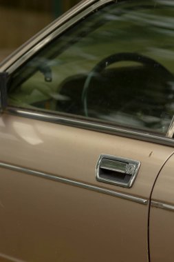 Bu görüntü, karmaşık ayrıntılar sunan bir araba kapısının yakın çekimini içerirken, arka planda bir direksiyon görebilmektedir, içerik ve derinlik eklenebilir