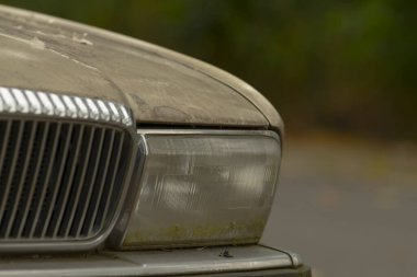 Kirli ve tozla kaplı çok kirli bir araba yolun kenarına park edilmiş, dikkat çekici bir şekilde göze çarpmasına neden oluyor.