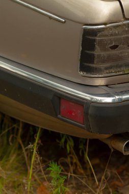 Bir araç, özellikle de kırmızı arka lambası olan bir araba şu anda yakınlardaki bir çimlerin üzerine park edilmiş durumda.