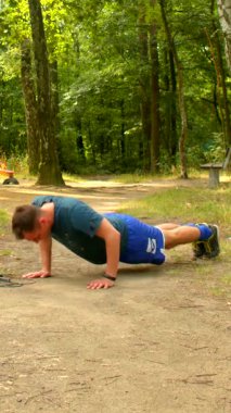 Bir fitness meraklısı dingin açık hava ortamlarında şınav çekerek güç ve kararlılık gösterir. Kendini adamışlığıyla izleyicilere ilham verir.