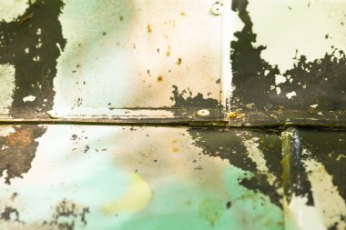 Bu paslı metal bir yüzeyin aşırı yakın çekimi. Bu yüzeyde boyaların soyulduğu yerler, aşınma ve yaşlanma izleri var.