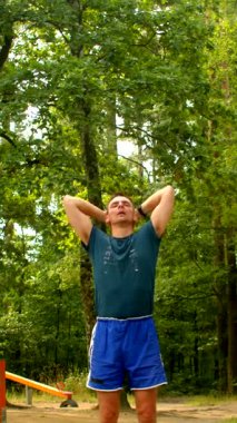 Mavi elbiseli bir adam huzurlu bir parkta canlandırıcı egzersizler yapar. Buna neşe dolu bir atlayış ve doğayı kucaklarken yansıma anları da dahil.