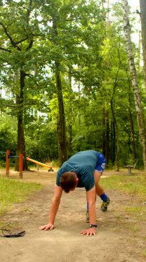 Bir adam doğada spor yapar, ormanda ayakkabı bağlar, parkta ip atlar, su içer, sonra şınav çeker, gücünü gösterir.