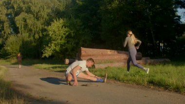 Bu video bir adamı bir yığın kütükle gösteriyor, azmi sembolize ediyor, sonra birkaç esneme ve aktif yaşam tarzını ön plana çıkaran bir parka geçiyor.