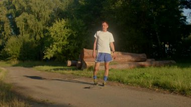 Bu video, bereketli bir ormanlık alanda dolambaçlı bir yolda yürüyen bir adamın güneş ışığını ve sakin atmosferi vurguladığı huzurlu bir yolculuğu gösteriyor.