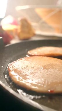 Tavada iki dilim jambon cızırdıyor, mutfağı aromayla dolduruyor. Yumuşak krepler onların yanında pişiyor, yemek hazırlama sanatı ve neşesini sergiliyor.