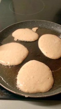 Dört pofuduk krep tavada cızırdıyor, havayı baştan çıkarıcı bir aromayla dolduruyor. Bu video, sıcak bir mutfakta yemek pişirmenin zevkli bir sürecini gösteriyor.