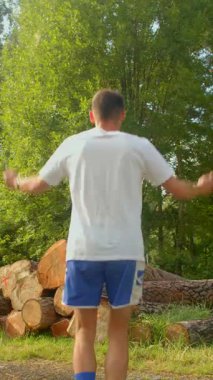 Gıcır gıcır beyaz gömlekli ve günlük mavi şortlu bir adam derin düşüncelere dalmış bir yığın kütüğün önünde dikiliyor.