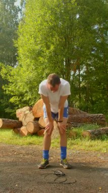 Sakin bir ormanda, bir adam büyük bir odun yığınıyla etkileşime girer, bükülür, çömelir ve onları inceler. Video onun doğayla olan bağlantısını vurguluyor.