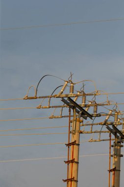 Ufuk boyunca uzanan uzun bir sıra enerji hattı, onların varlığını artıran geniş mavi gökyüzünün arka planına karşı kurulur.