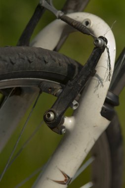 Bu, ayrıntıları ve renkleri arttıran canlı yeşil bir arkaplan üzerine kurulmuş bir bisiklet freninin karmaşık bir yakın plan fotoğrafı.