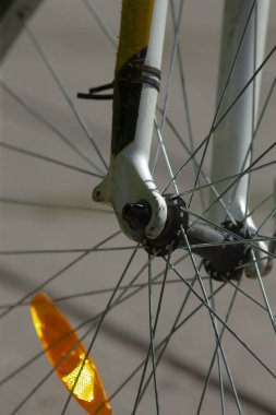 Bu resim, turuncu yansıtıcı da dahil olmak üzere karmaşık bileşenlerini belirgin bir şekilde gösteren bir bisiklet tekerleğinin ayrıntılı yakın çekim görüntüsünü içerir.