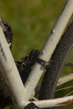 Bu resim, canlı yeşil bir arkaplan önünde konumlanmış bir bisikletin detaylı bir yakın çekimini sergiliyor, özelliklerini güzel bir şekilde vurguluyor