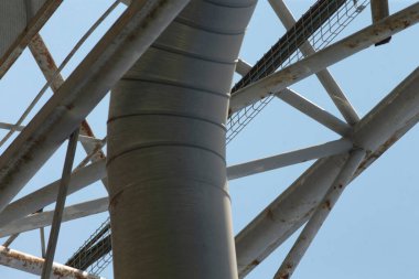 Bu resim, arka planda parlak mavi bir gökyüzüne karşı güzelce tezat oluşturan karmaşık bir metal yapının detaylı bir yakın çekimini içeriyor.