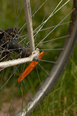 Bu, bisiklet tekerleğini gösteren yakın plan bir görüntü. Üzerinde turuncu bir yansıtıcı var. Görüş ve güvenlik sağlıyor.