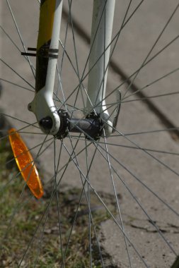 Bu, tekerleğin ve bileşenlerinin detaylarını vurgulayan turuncu yansıtıcının yer aldığı bir bisiklet tekerleğinin yakın görüntüsü.