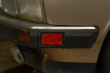 Bu, üzerinde parlak kırmızı bir park lambası bulunan bir araba tamponunun detaylı bir yakın çekim görüntüsü.