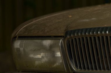 Bu, kirli bir araba kaputunun yakın plan görüntüsü ve beraberinde gelen farlarla birlikte, tipik yıpranma belirtileri gösteriyor.