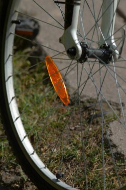 Bu görüntü, üzerine turuncu bir yansıtıcı iliştirilmiş bir bisiklet tekerleğinin yakın plan görüntüsünü içeriyor.